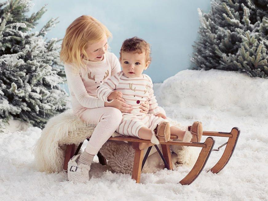 a young girl and boy sitting on a sled in the snow