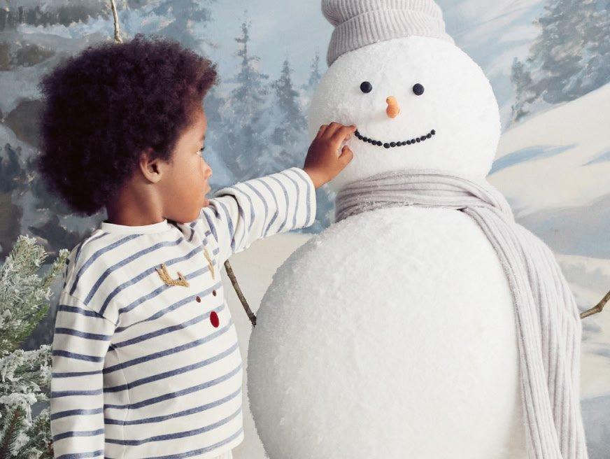 a young boy is playing with a snowman in the snow