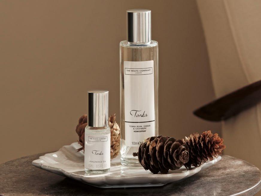 a couple of bottles of perfume sit on a table with pine cones