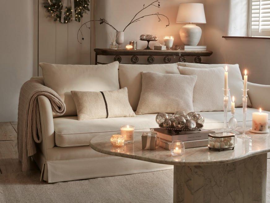 a living room with a white couch, candles and a table