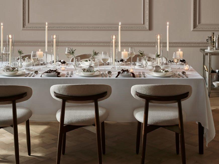 a table with a white tablecloth and white chairs with candles