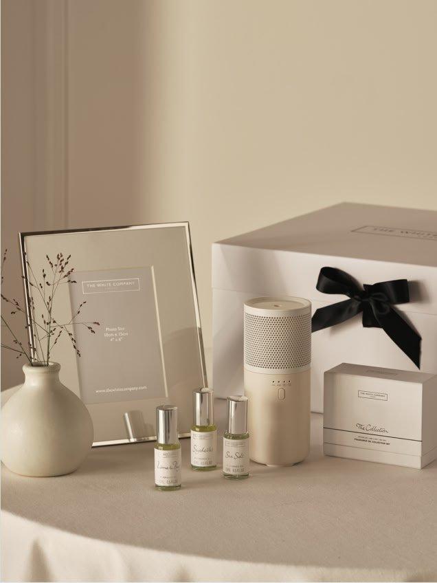 a table with a white box, a vase, a picture frame and a vase of