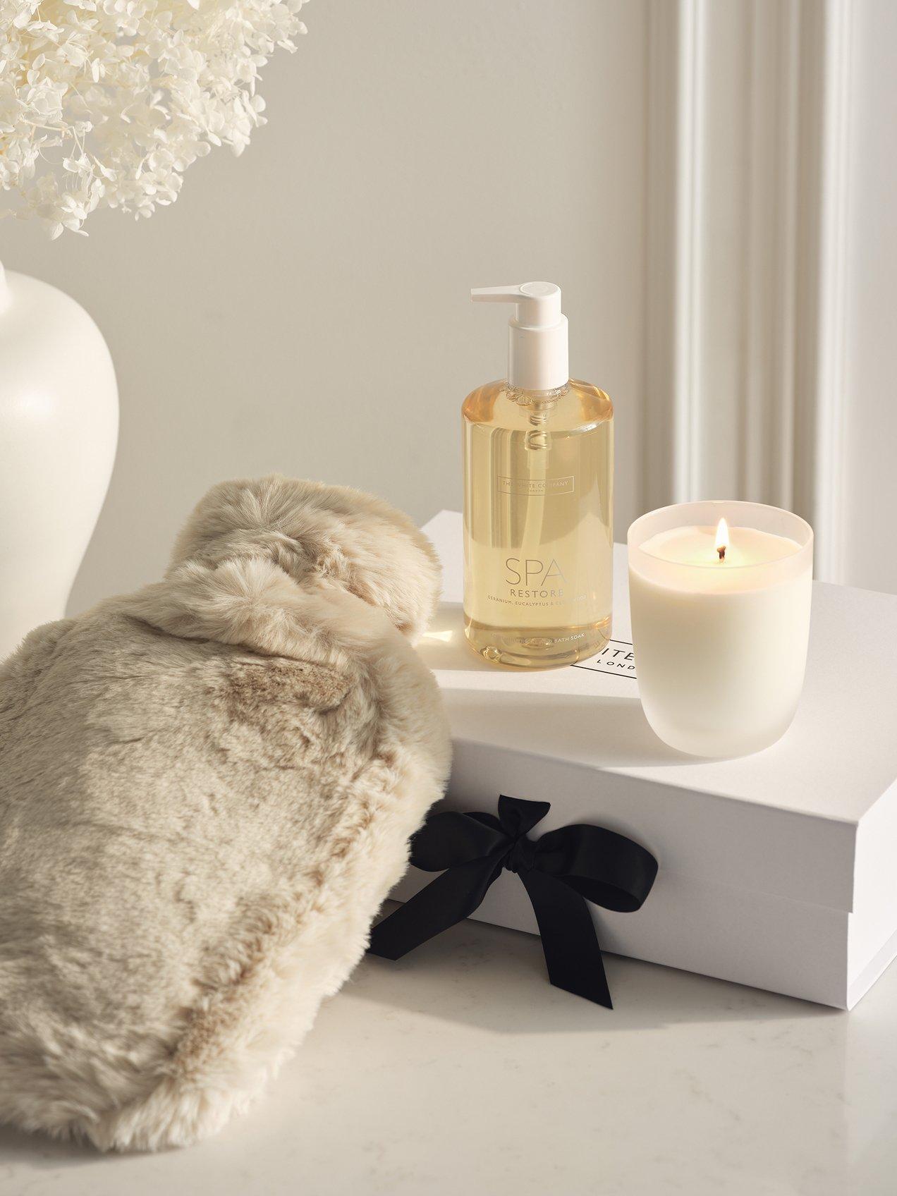 a white box with a candle, a hot water bottle and a candle holder