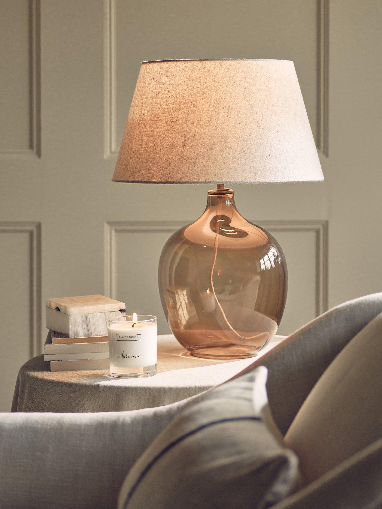 a table with a lamp and a book on it next to a chair