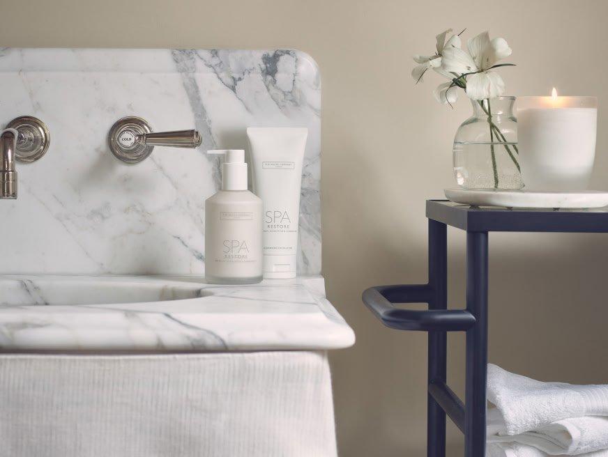 a bathroom sink with a candle and a vase of flowers