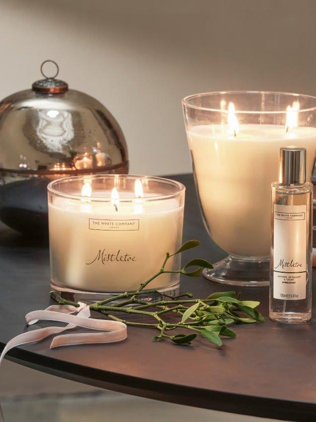 a table with candles and a plant on it next to a mirror