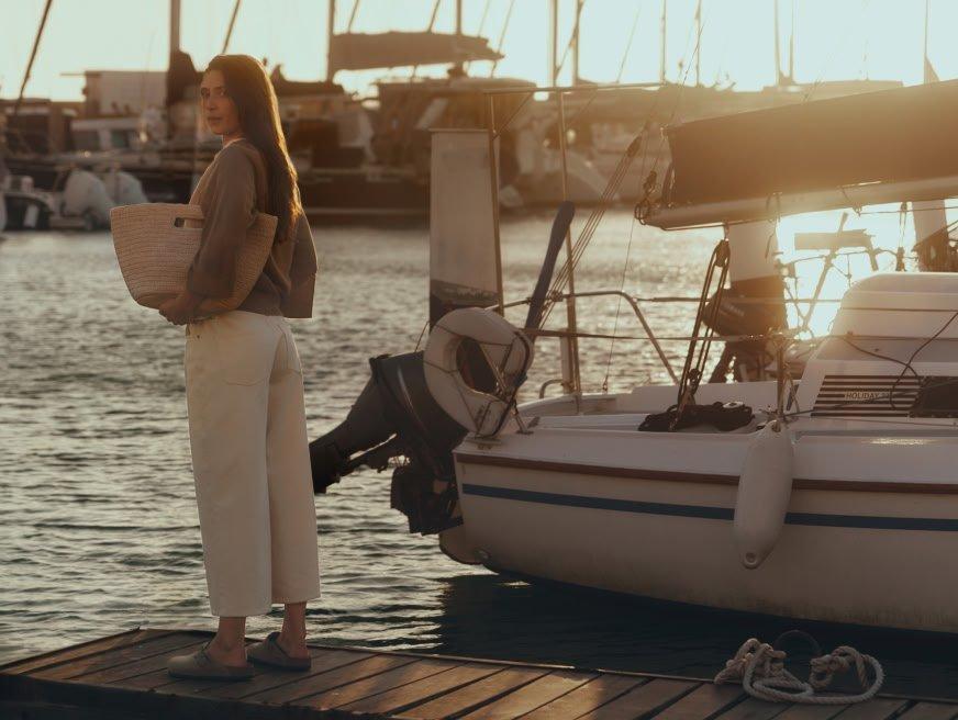 a woman standing on a dock next to a boat
