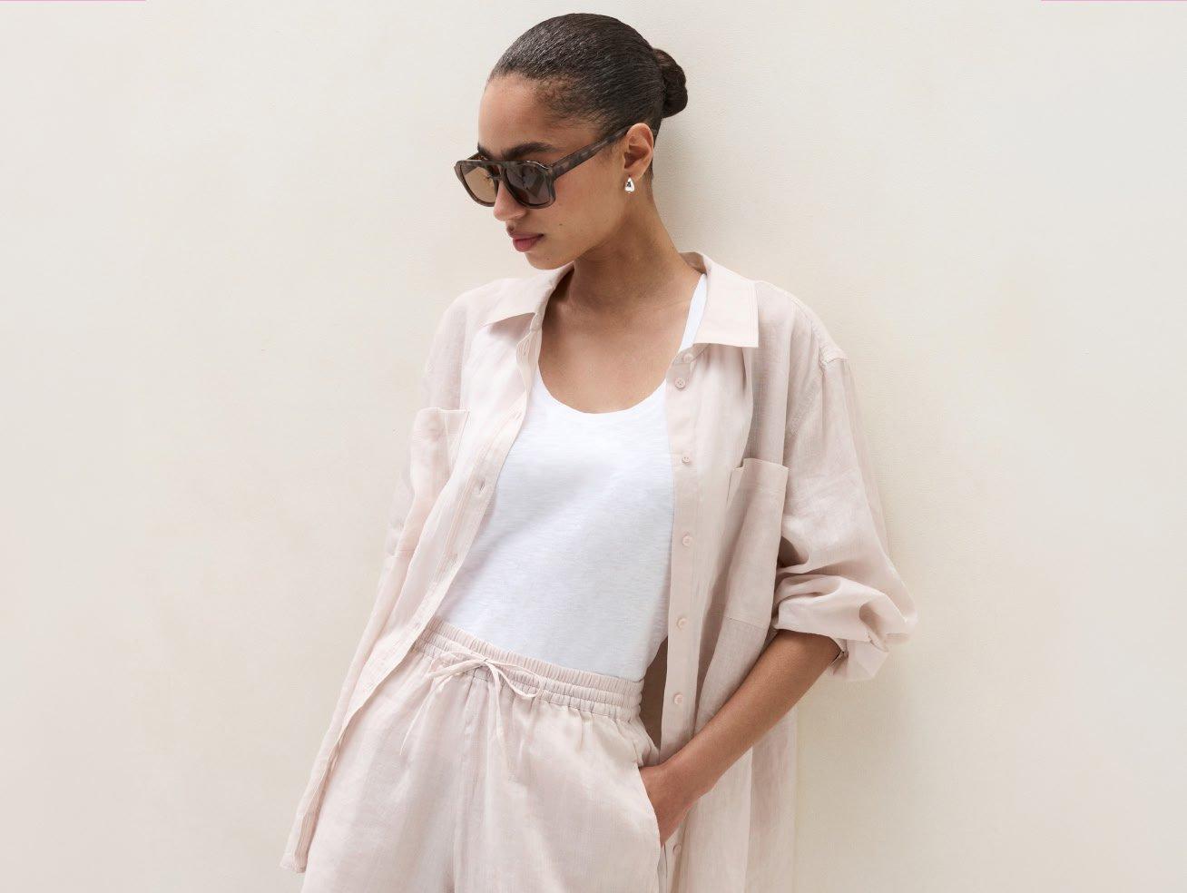 a woman in a white shirt and shorts leaning against a wall