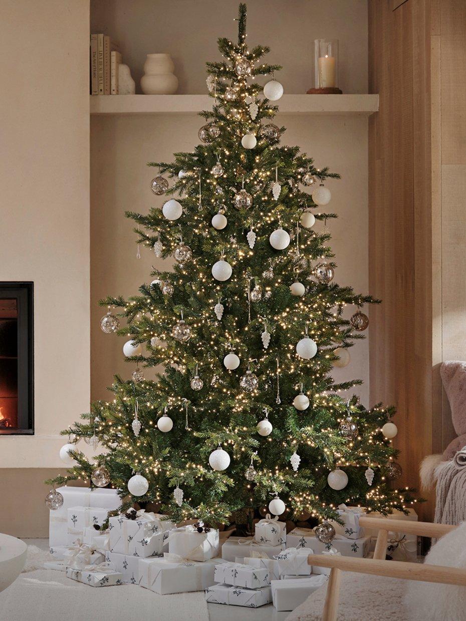 a christmas tree is lit in a living room with a fireplace