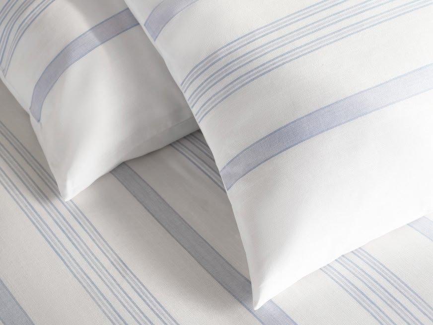 a close up of a bed with white and blue striped pillows
