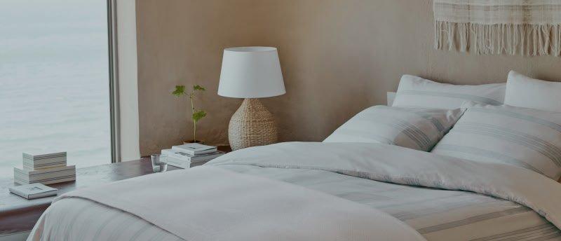 a bed with a white comforter and pillows in a bedroom