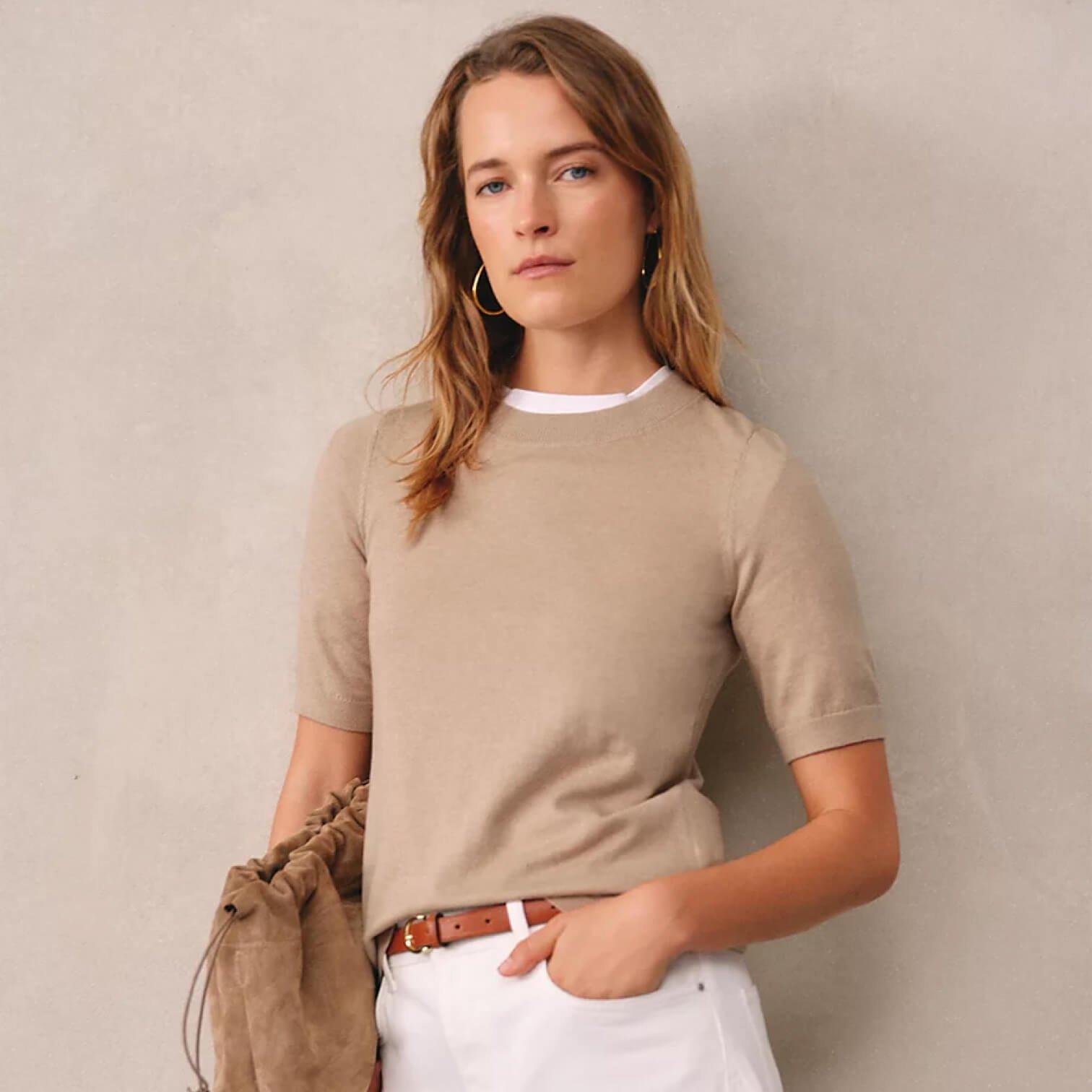 a woman in a white dress standing against a wall