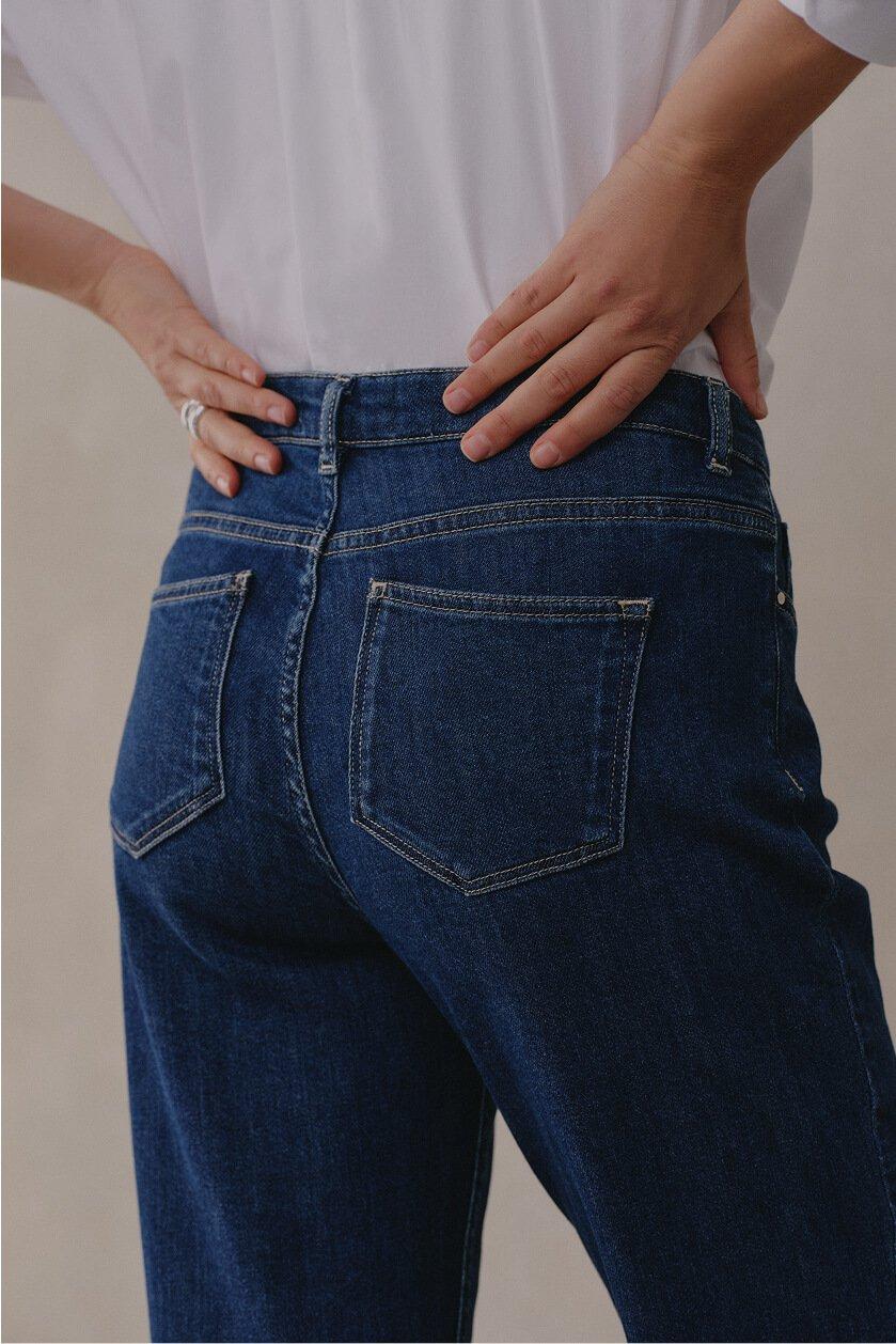 a woman in a white shirt and blue jeans with her hands on her hips