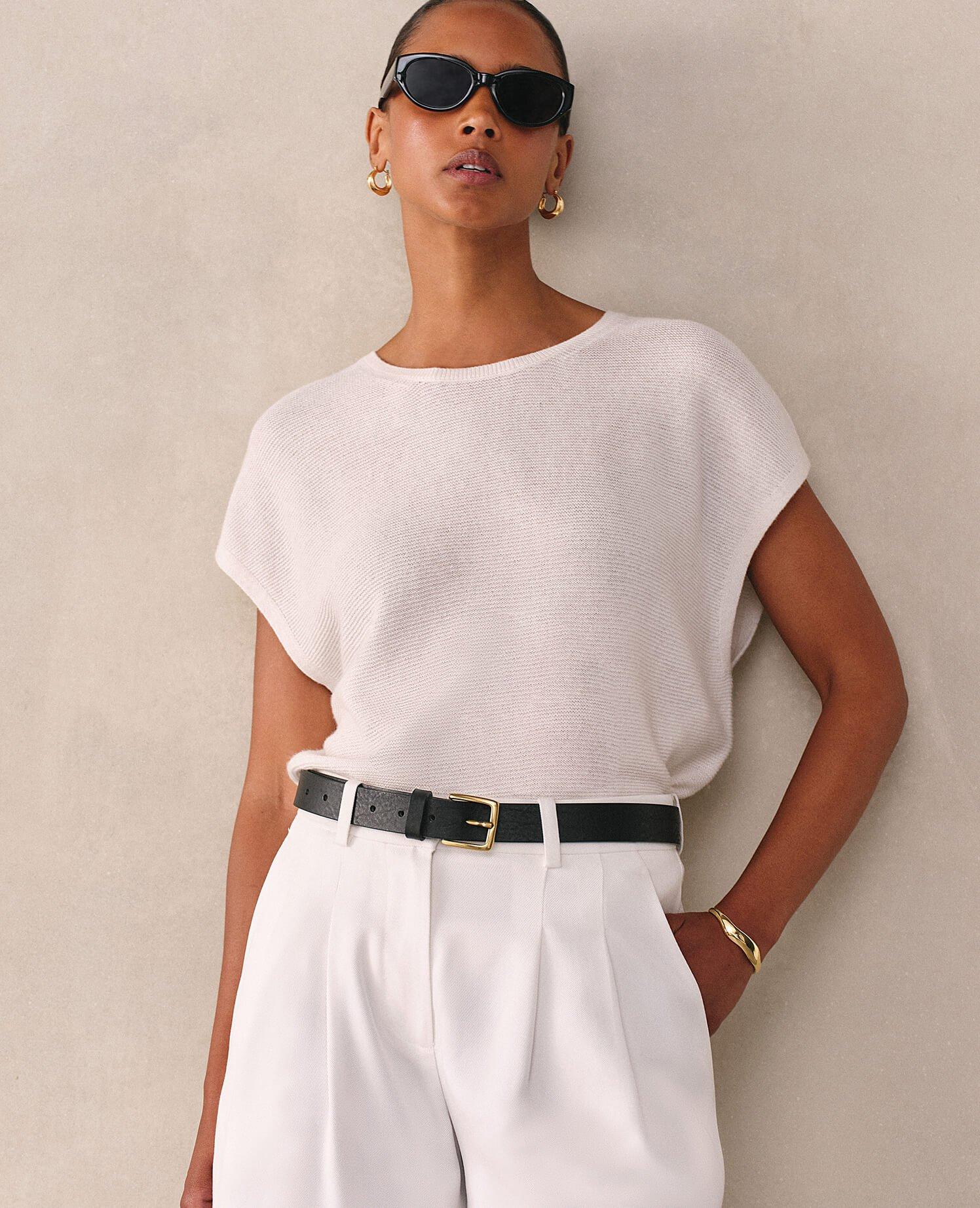 a woman in a white dress standing against a wall