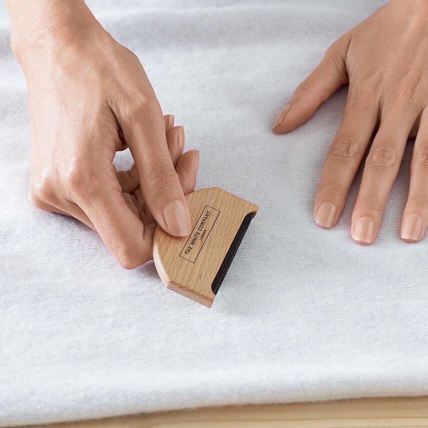 a person using a wooden tool to remove a stain from a white cloth