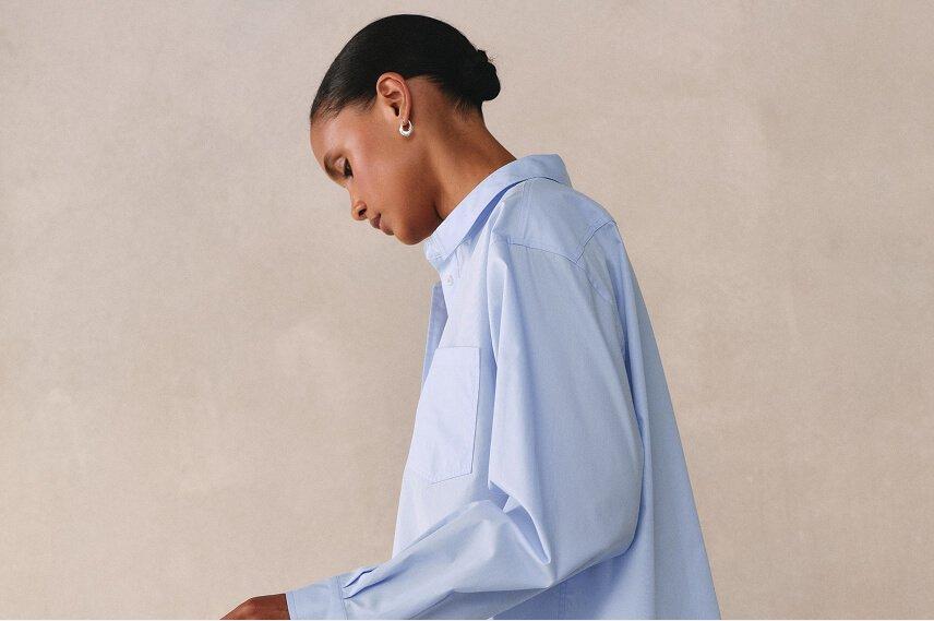 a woman in a blue shirt and jeans holding a cell phone