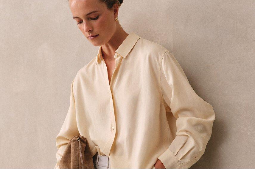 a woman in a white shirt holding a purse and a book