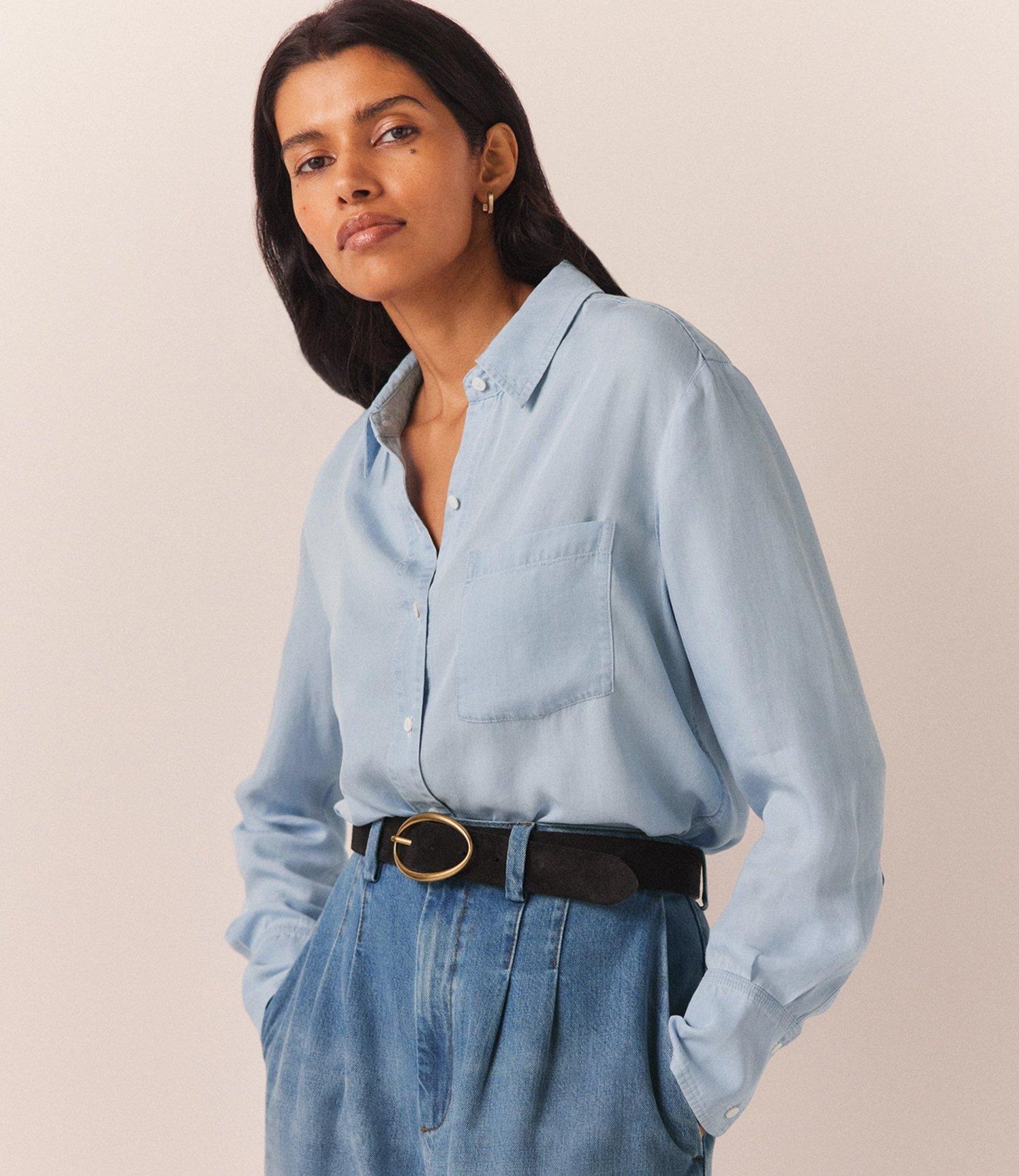 a woman in a blue shirt and black pants standing