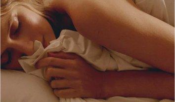 a woman laying in bed with a white sheet covering her