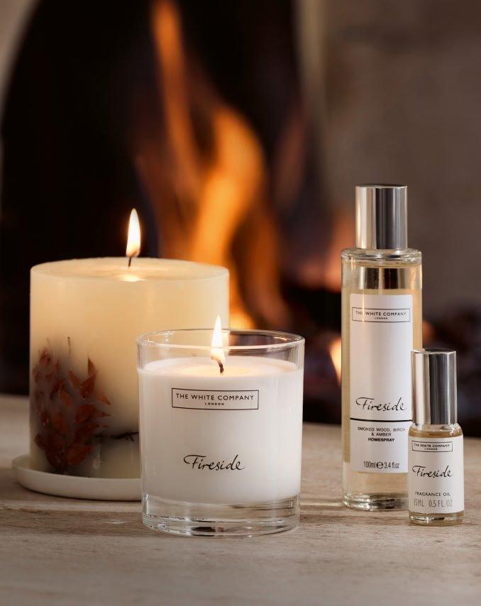 a group of candles and a bottle of perfume sit on a table