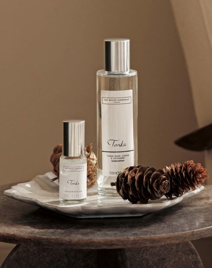 a couple of bottles of perfume sit on a plate with pine cones