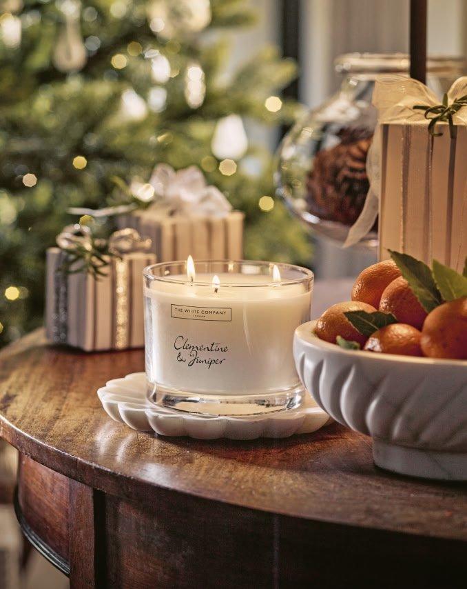 a table with a candle and oranges on it next to a christmas tree