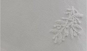 a close up of a white sheet with a small flower on it