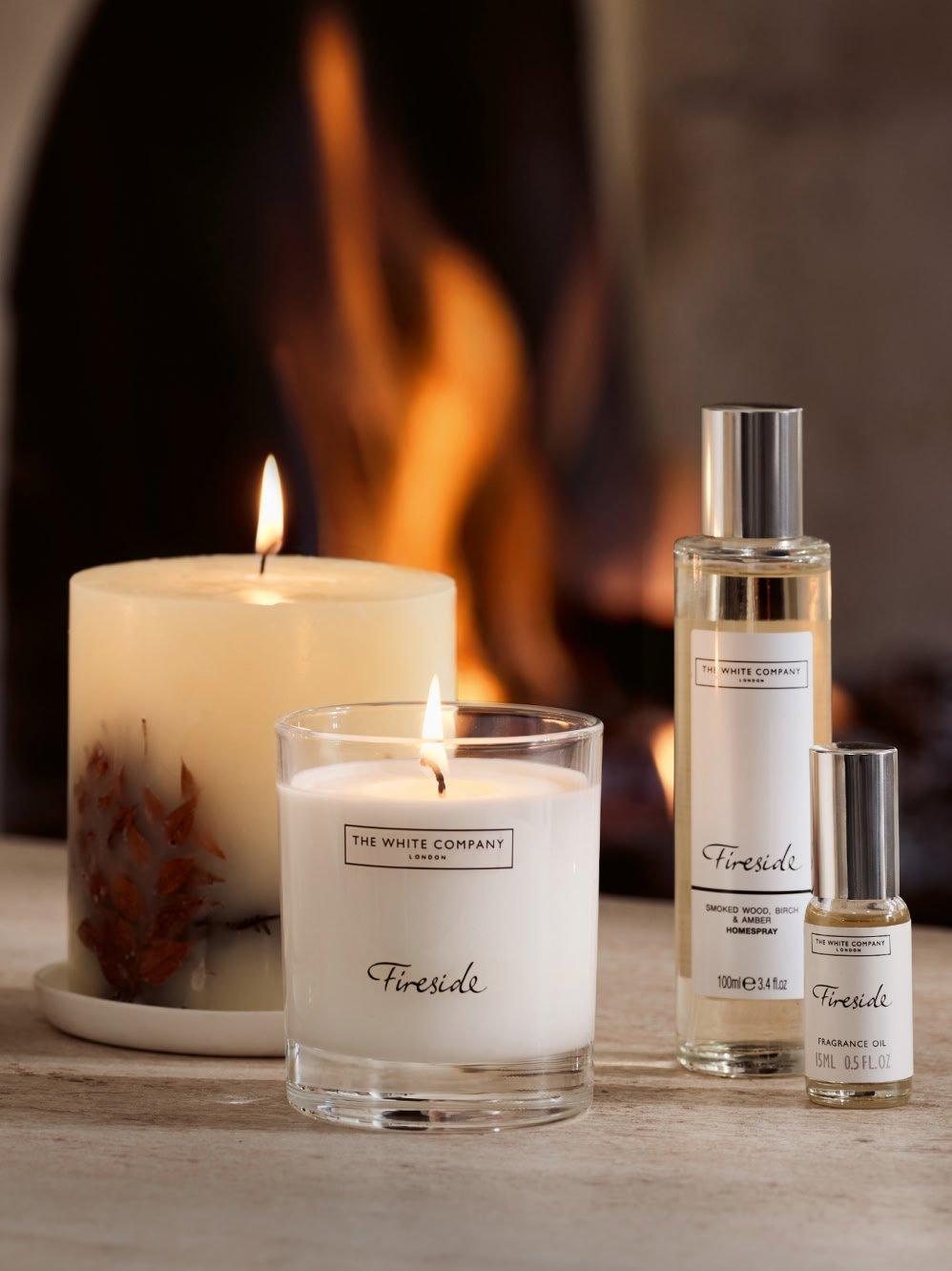 a group of candles and a bottle of perfume sit on a table