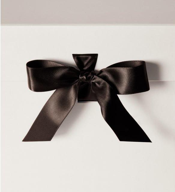 a black bow on a white box with a white ribbon