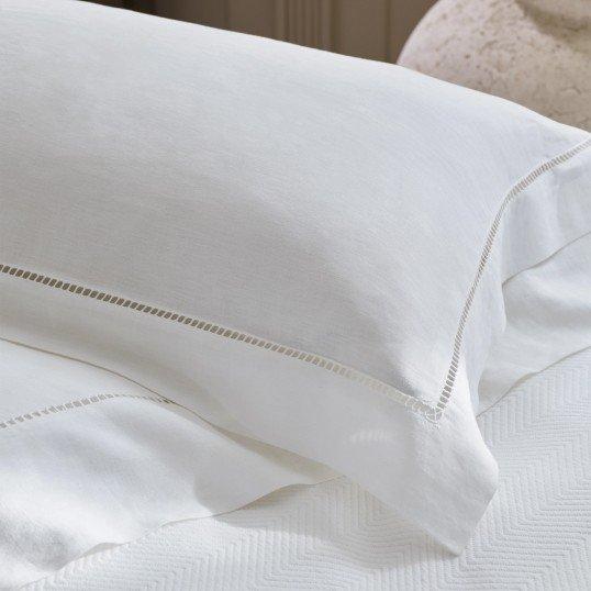 a close up of a white bed with pillows and sheets