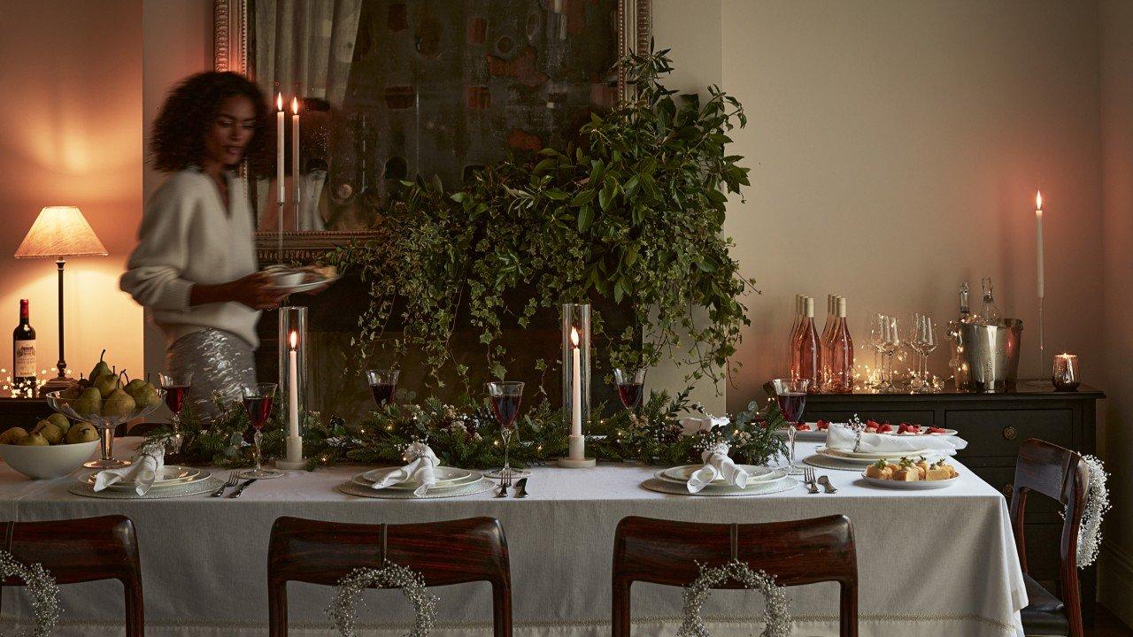 a woman standing in front of a table with a candle on it