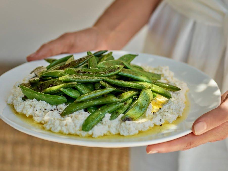 a person holding a plate of food with green beans on it