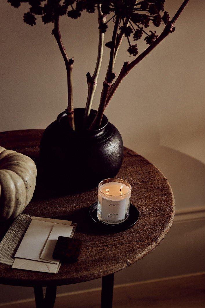 a candle on a table with a vase of flowers and a pumpkin