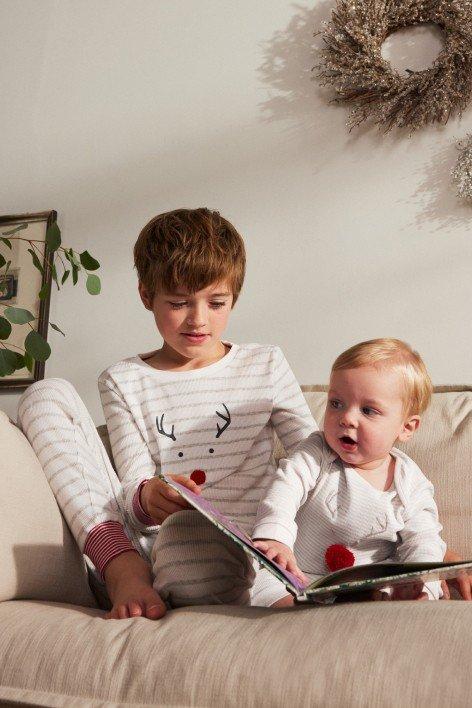 a boy and girl sitting on a couch reading a book