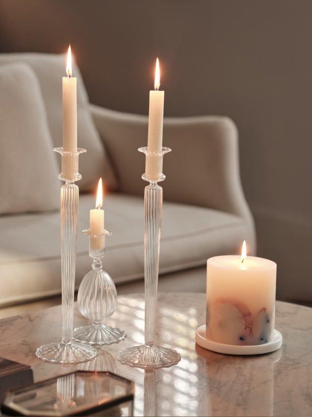 a table with three candles and a glass vase on it