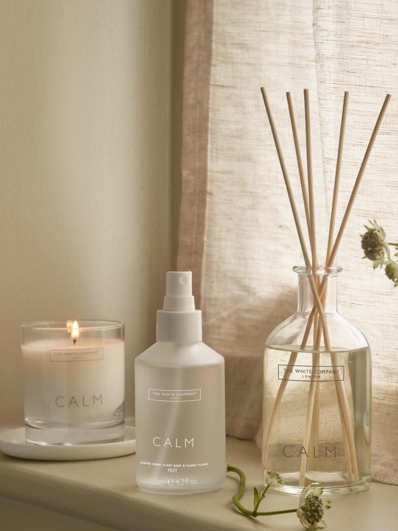 a window sill with a vase of flowers and a candle