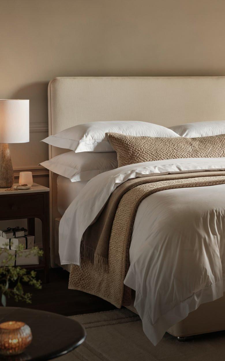 a bed with a white comforter and pillows in a bedroom