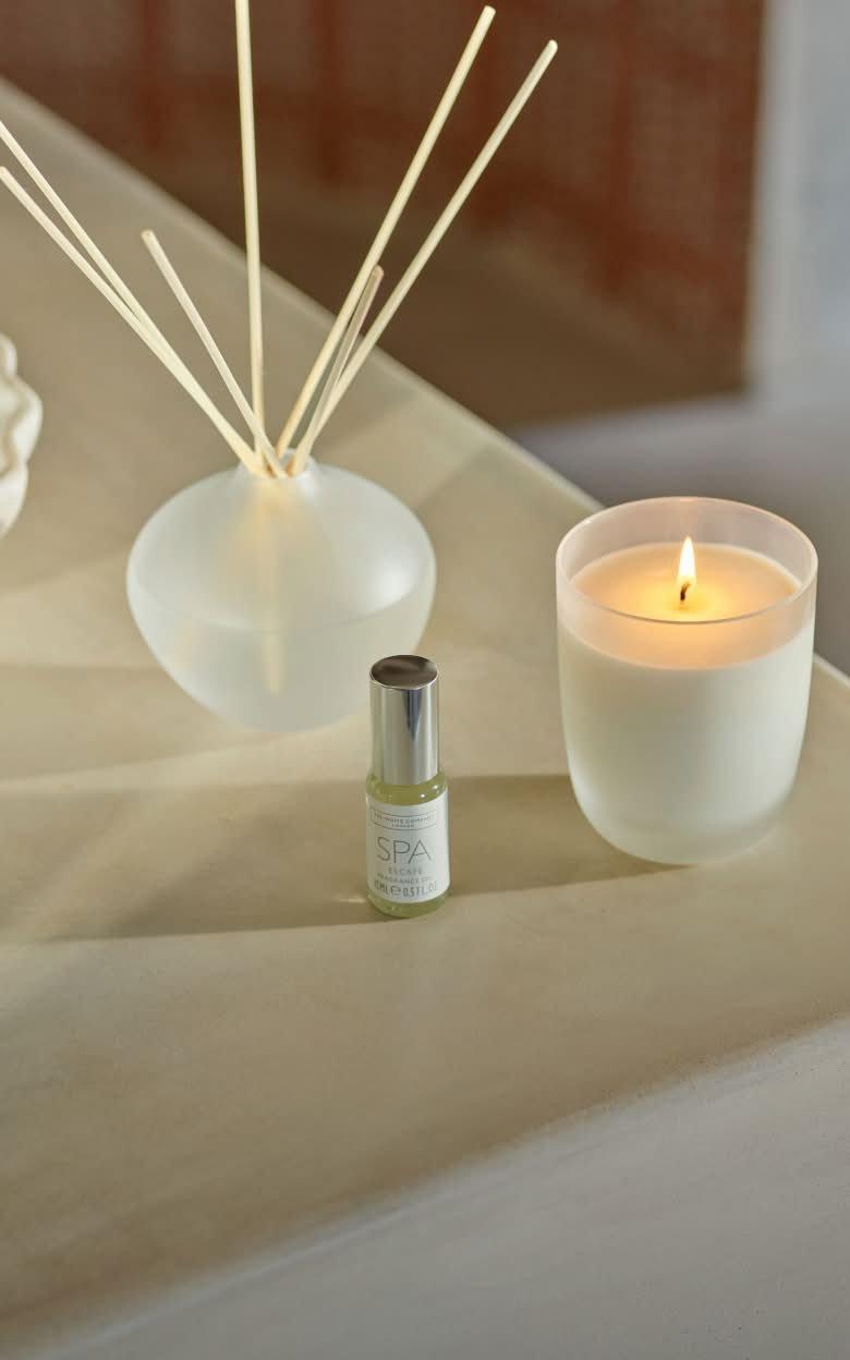 a candle and a bottle of perfume sit on a table
