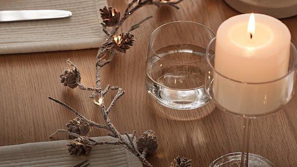 a candle and a glass on a table with a fork and knife