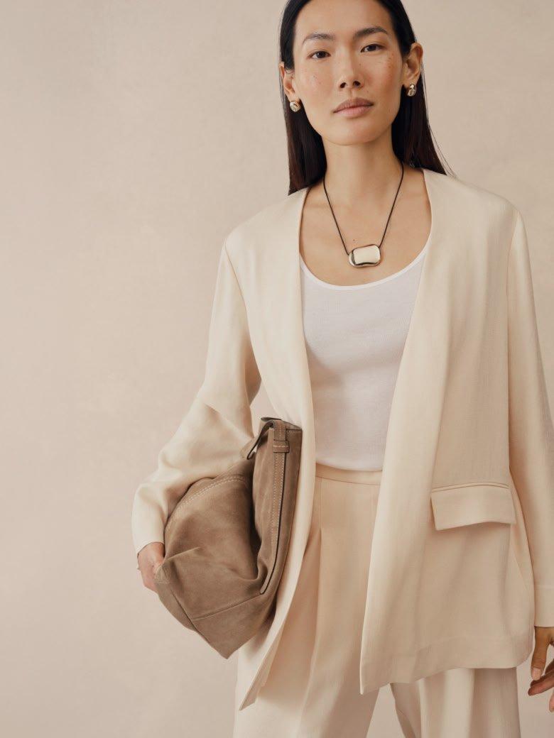 a woman in a white blazer and skirt holding a purse