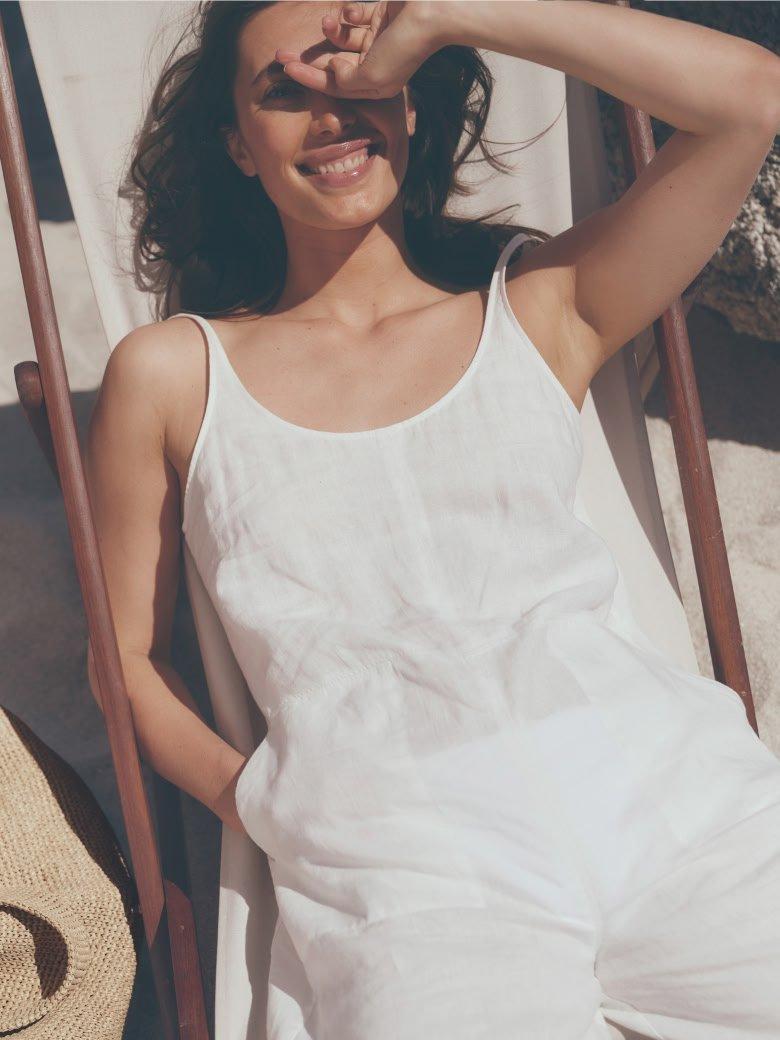 a woman in white dress on beach with bag on shoulder