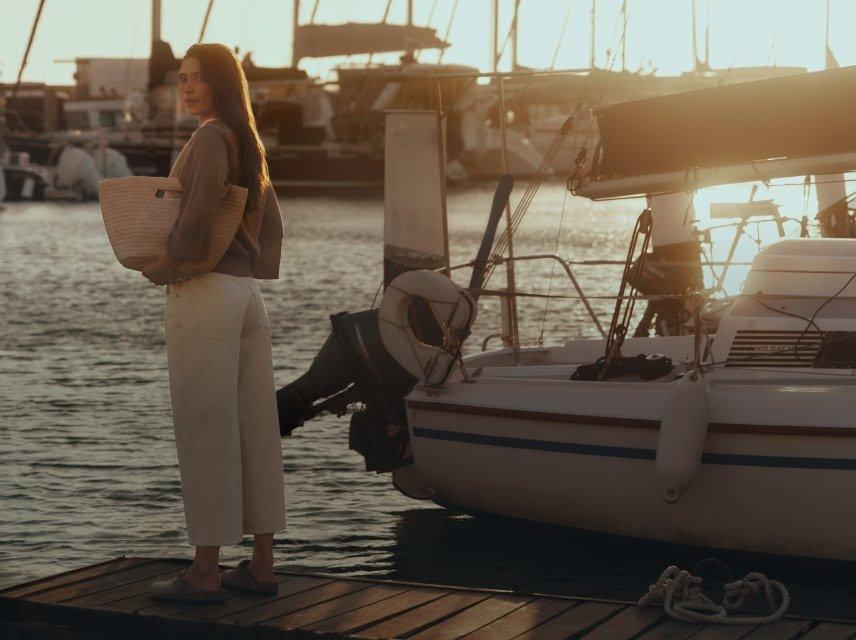 a woman standing on a dock holding a basket of goods