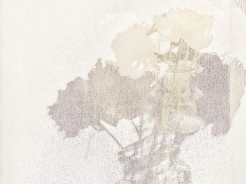 a vase of flowers on a table with a shadow of a person