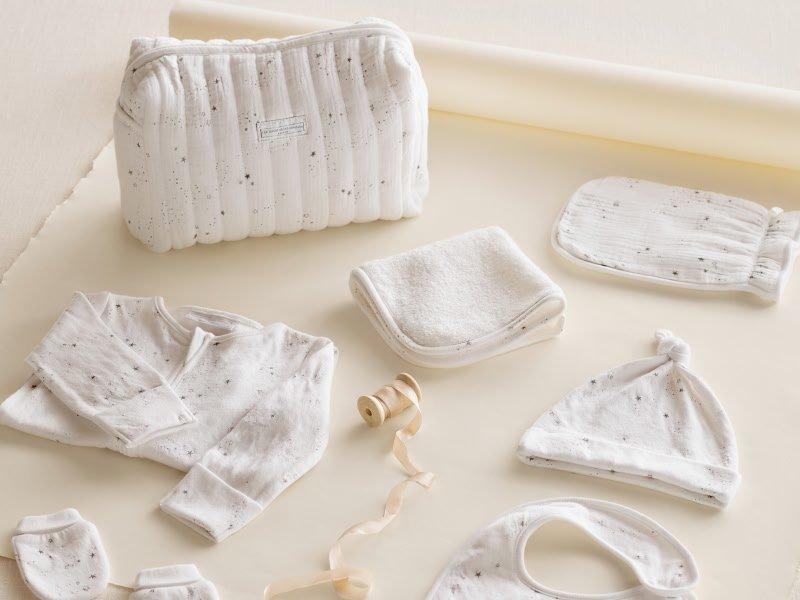 a white baby outfit and accessories laid out on a table