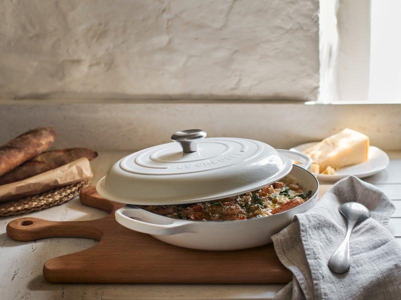 a white casserole dish with a lid on top of a wooden cutting board