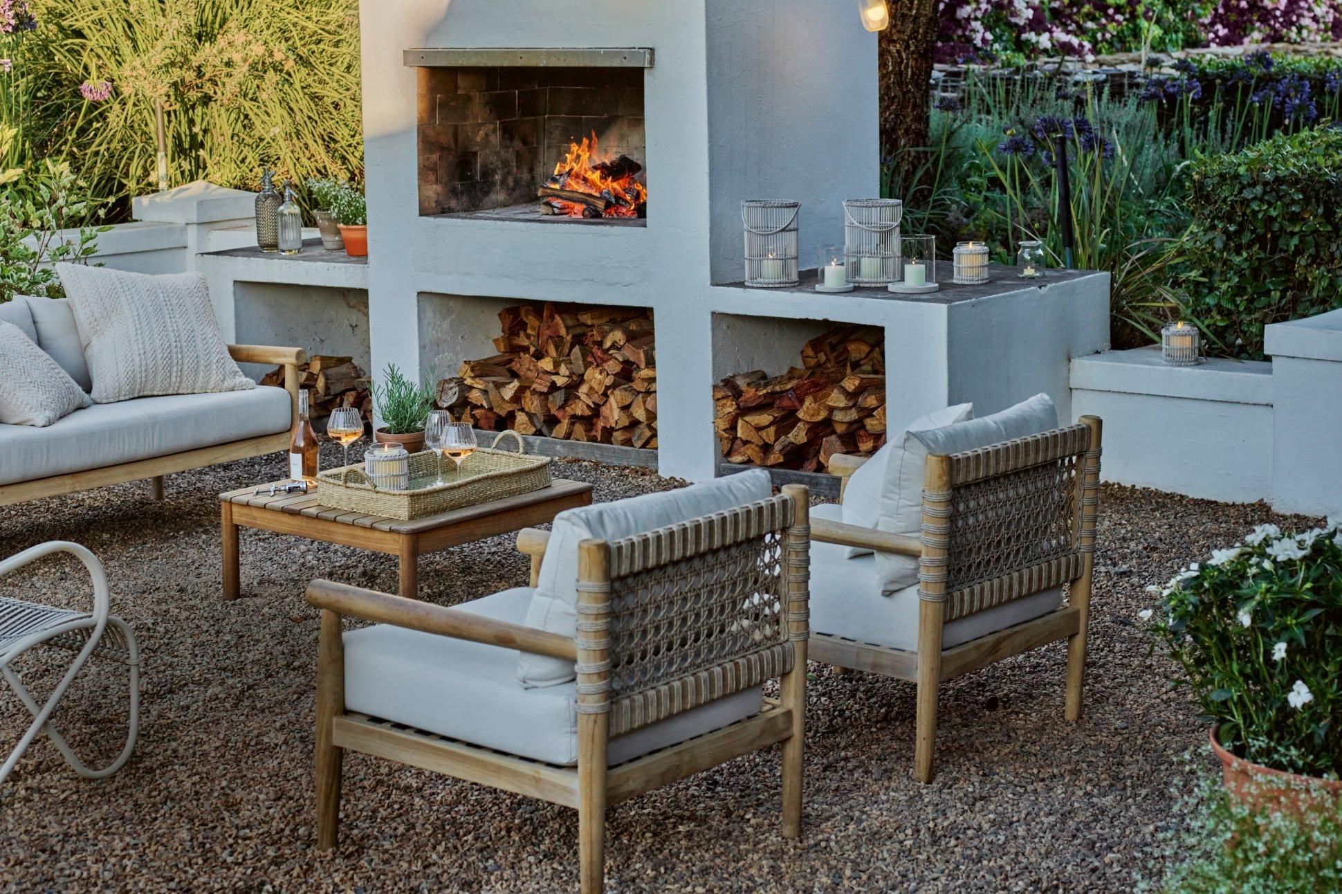 a white fireplace in a garden setting with chairs and tables