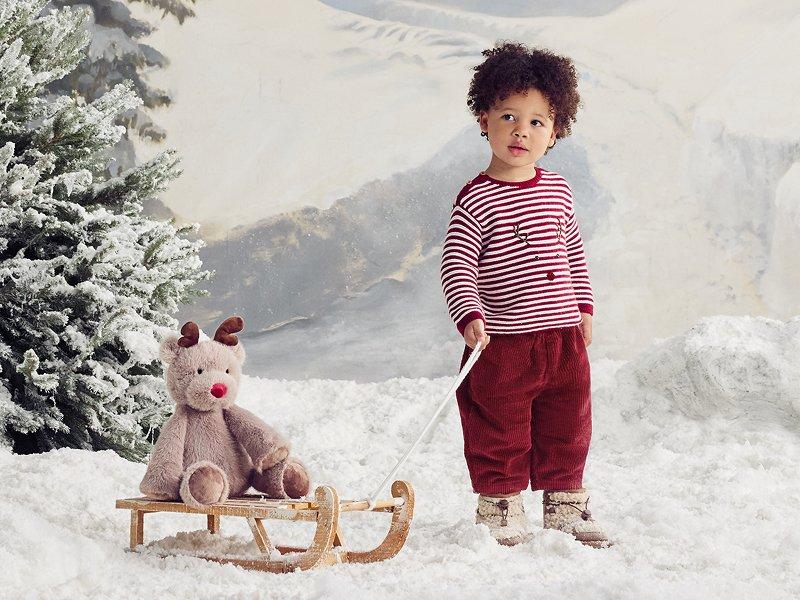 a young boy pulling a sled with a stuffed bear on it