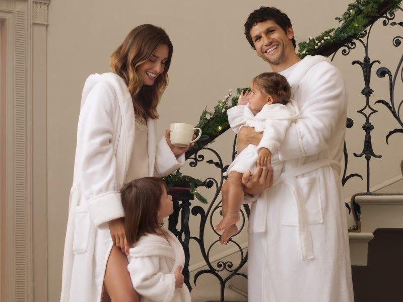 a man and woman in white robes holding a baby and a cup