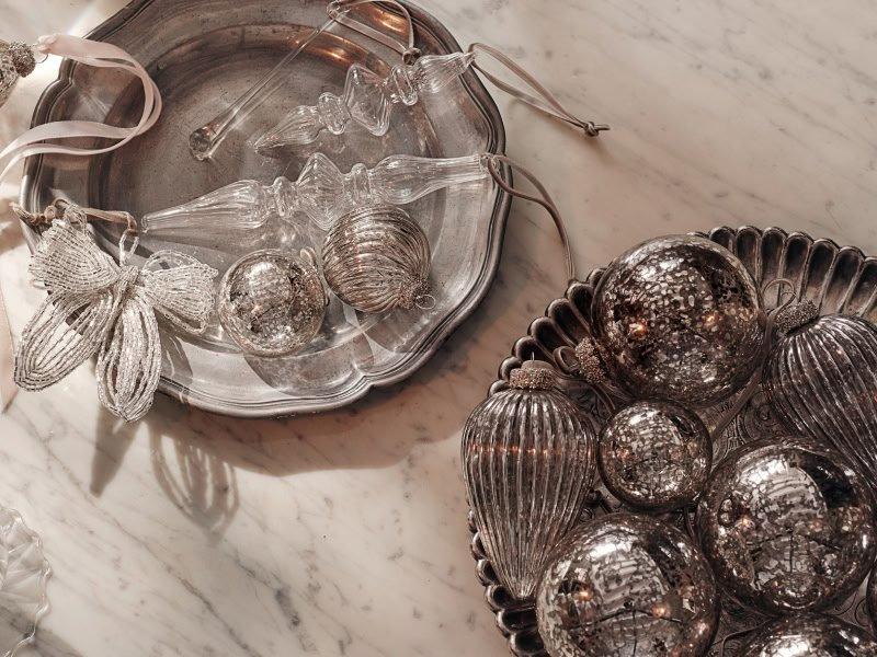 a marble counter top with silver and glass ornaments and a candle