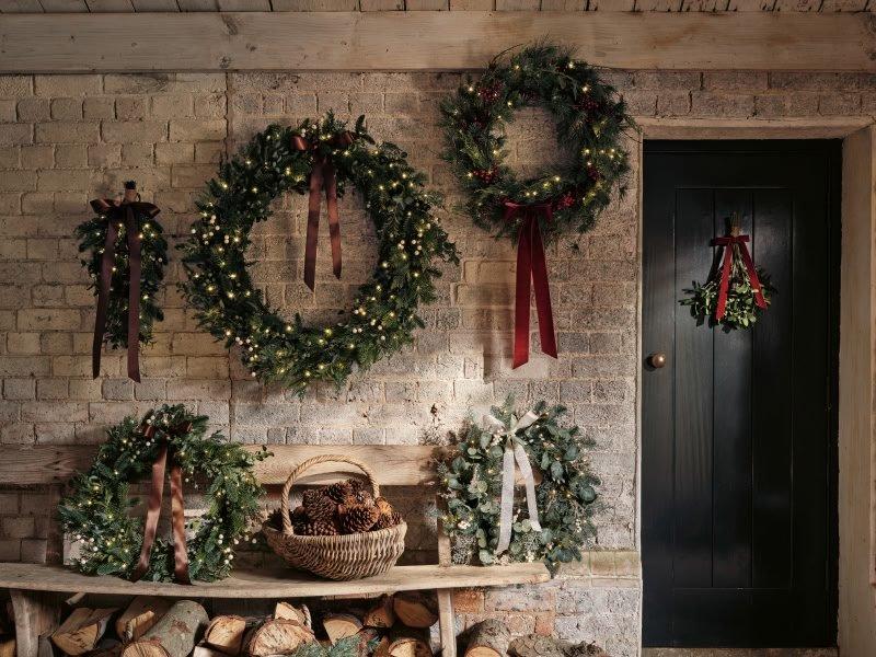a brick wall with wreaths hanging on it and a bench
